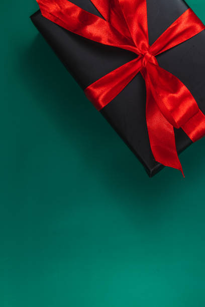 istock Banner with black gift box with red ribbon and bow on green background 2173667624