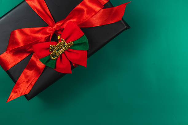 Gift box with red bow and Merry Christmas, on green background High quality photo