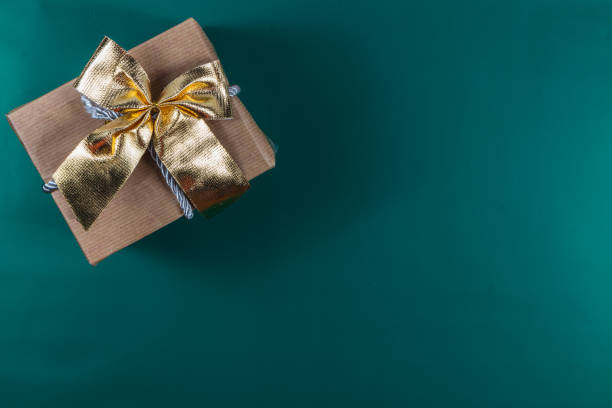 istock Christmas gift box with golden bow on green background 2173668481