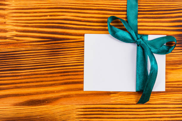 istock Blank note with green ribbon on right on wooden board, concept 2173670955