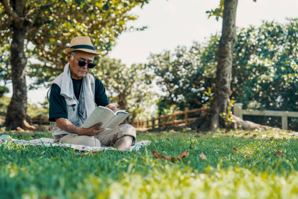 Senior man reading a book in a park on a sunny day
