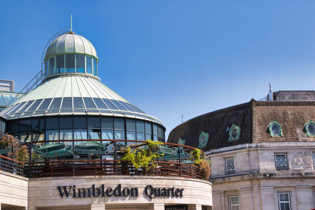 Wimbledon Quarter Architecture Under Blue Sky in Wimbledon, UK A bright blue sky over the Wimbledon Quarter, showcasing a modern glass structure with a dome and a traditional building with a rounded roof. The area is lively and inviting, perfect for dining and leisure. wimbledon seats stock pictures, royalty-free photos & images
