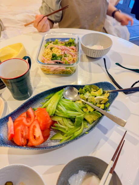 Glass plates wit noodle Salad with ham and avocado slices served on a white table