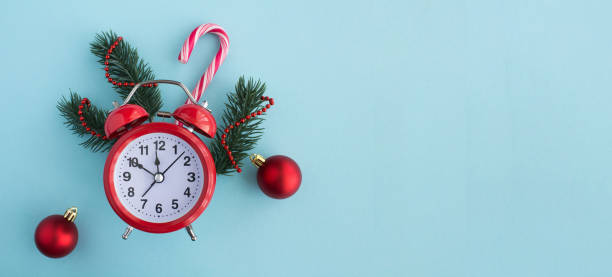 Red alarm clock and Christmas composition on the blue background. Copy space.