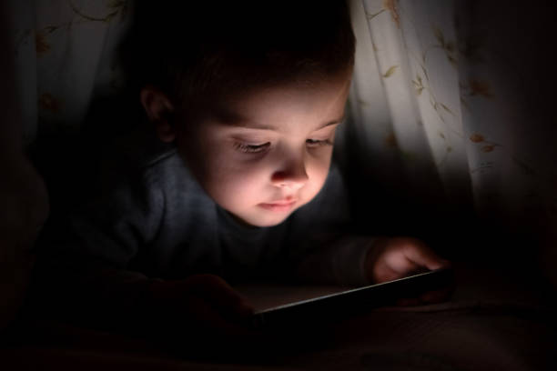 istock Cute boy secretly watching video on phone under the blanket 2173690866