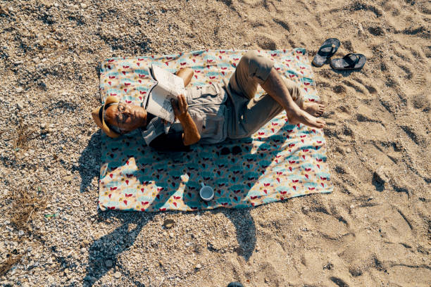 Senior man reading a book on a beach on a sunny day