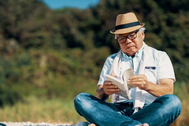 Senior man reading a book on a beach on a sunny day