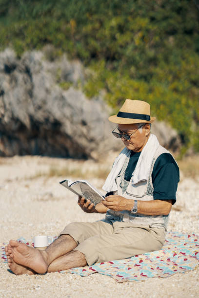 istock Senior man reading a book on a beach 2173693969
