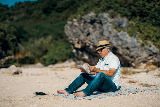 istock Senior man reading a book on a beach 2173694033