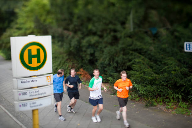 Front view of young man's body jogging on roadside, sports clothing. Copy space available . Periphery defocused.