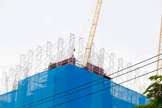 Blue canvas around construction of new building in street Wanghin Road in Bangkok Ladprao. Metal gorders are placed for new floor and columns. In background is part of a crane