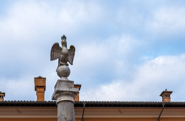 Perspective of crowned eagle perched on a globe decorating the top of marble roman pillar rising against the sky in the italian city of Ravenna