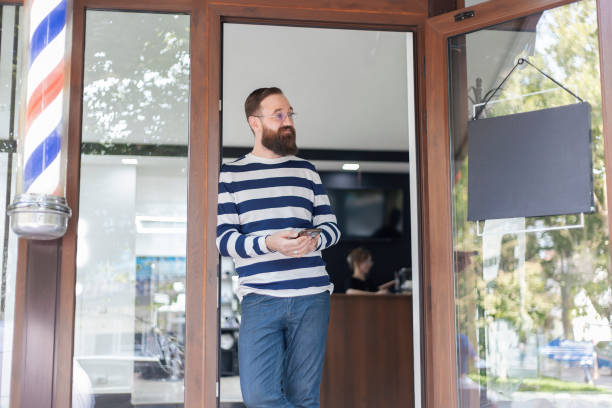 istock Bearded man standing outside barbershop with  sign 2173714040