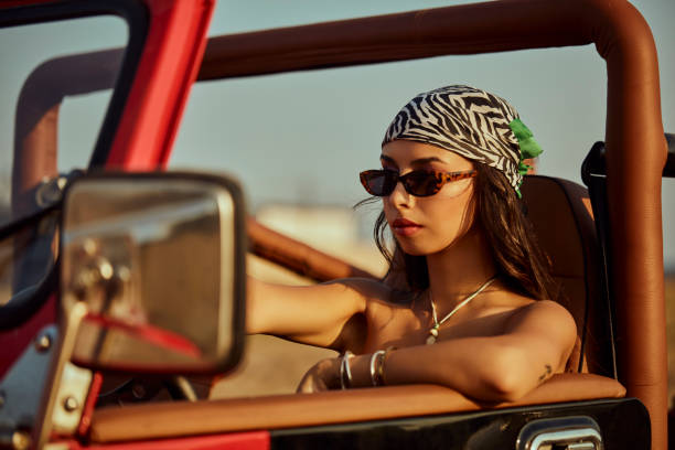 A beautiful woman explorer driving a convertible jeep.