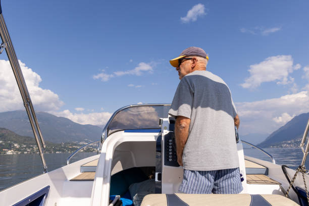 A man wearing a cap steers a boat on a sunny day, enjoying the open water and beautiful weather.