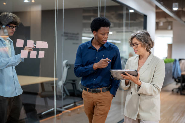 istock A group of financial analysts walk through a modern office, holding digital tablets and engaging in conversation. The sleek, professional environment features glass-walled conference rooms, highlighting an atmosphere of collaboration and corporate culture 2173725927