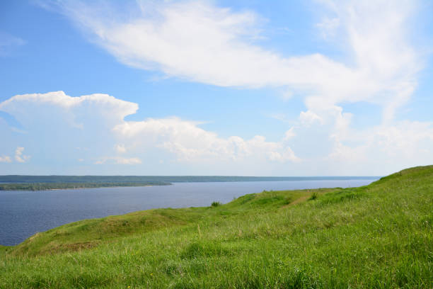 istock a grassy hill with a lake in the background and blue sky with clouds 2173731157
