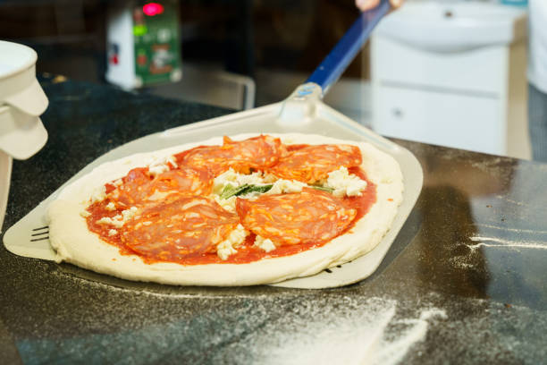 Chef preparing and spreading pizza dough on a pizza shovel before putting it in the oven