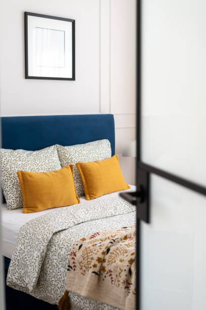 Comfortable bedroom with blue headboard and yellow cushions in a modern home interior