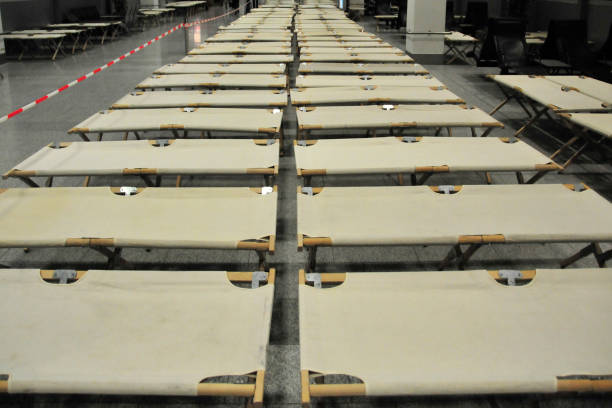 Folding cots aka airport cot. These cots are typically set up in airports during flight delays, cancellations, or emergencies when passengers need to stay overnight due to disruptions. They provide a temporary and portable resting solution for stranded travelers and are usually stored and deployed as needed. They are also employed to provide emergency shelter in large spaces, such as sports arenas and industrial buildings when catastrophes, natural or otherwise, require the emergency evacuation of residents.