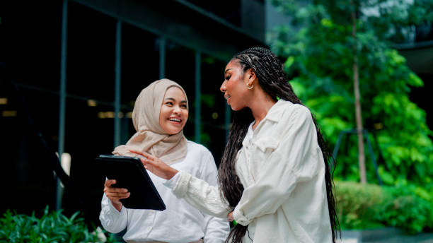 istock Two young women looking at something interesting in the digital tablet together while resting in their company's green area. 2173750216