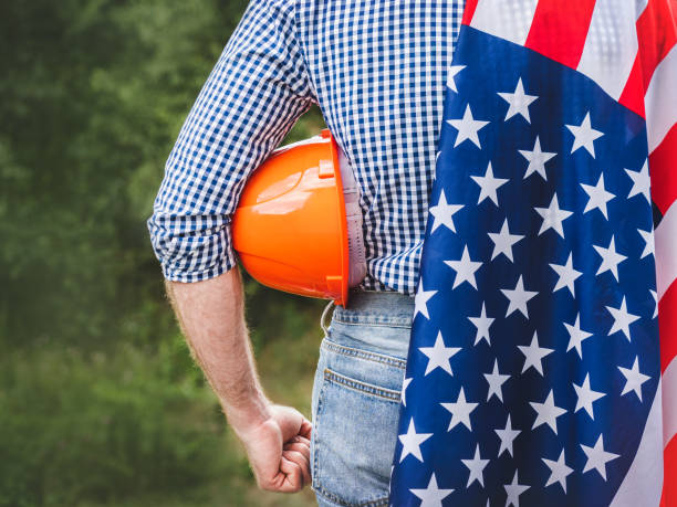 istock Attractive man in work clothes holding American Flag 2173752608