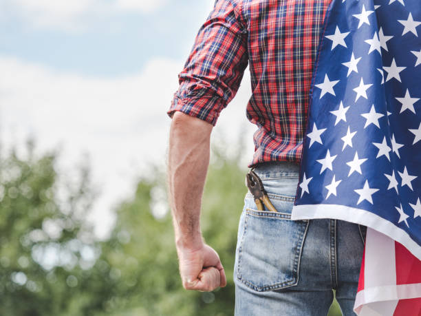 istock Attractive man in work clothes holding American Flag 2173752624