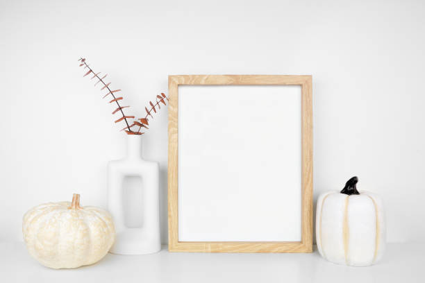 istock Mock up portrait wooden frame with fall branches and pumpkin decor on a white shelf against a white wall 2173752796