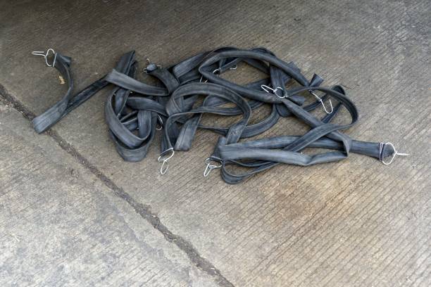 A black rubber bands are piled on the cement floor.