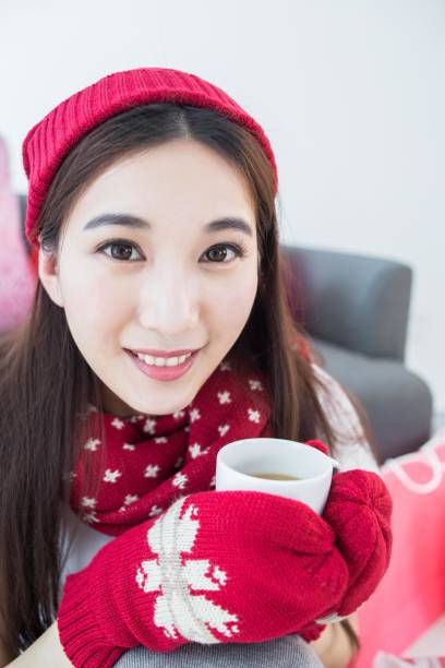 A young woman in red winter clothes is drinking from a cup