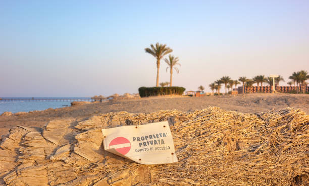 Private property sign on a palm tree trunk on a beach at sunset, Marsa Alam, Egypt.