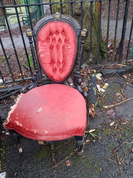 A velvet red abandoned used chair on a pavement