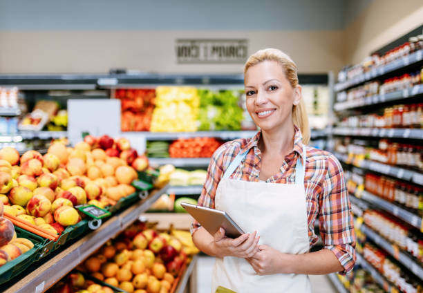istock Mature employee woman working in supermarket and using digital tablet 2173775384