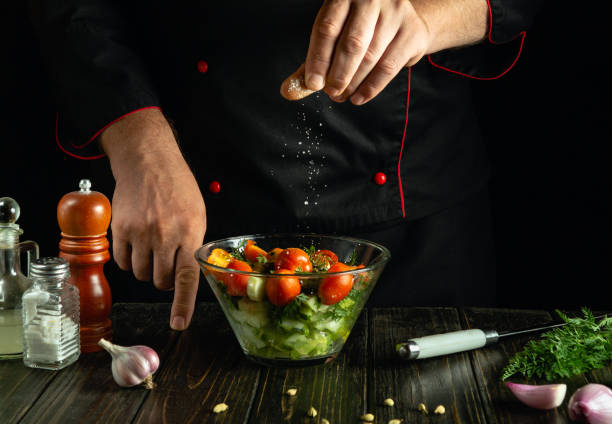 istock A cook at the kitchen table prepares a vegetable mixture for dinner. The chef adds salt to a vegetable salad with his hands. Vegetable diet menu for a restaurant or hotel 2173778441