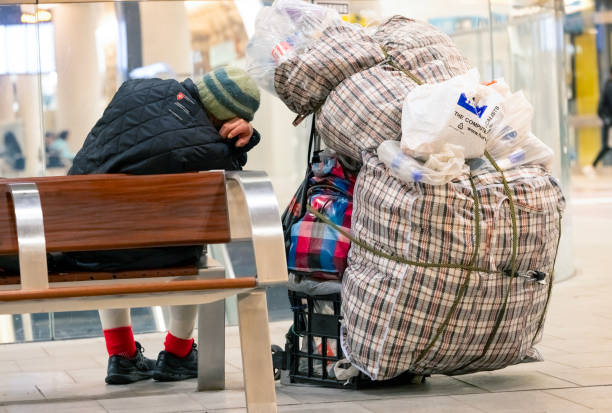 Sydney, Australia - September 23, 2024: Sleeping homeless man at the Central train station in Sydney with his belongings