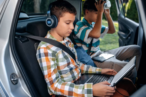 istock Teenagers in car using digital tablet while sitting on back seat before going to school 2173801140