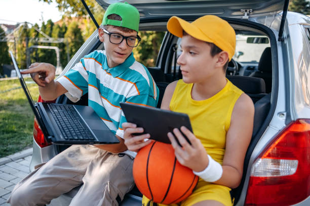 istock Teenagers sitting in car trunk using digital tablet before leaving on sport training 2173801227
