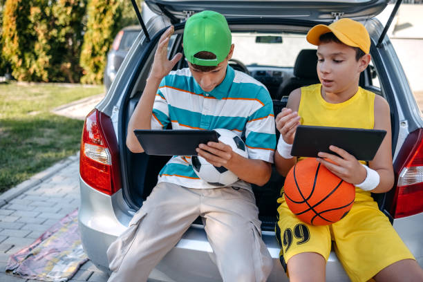 istock Teenagers sitting in car trunk using digital tablet before leaving on sport training 2173801228