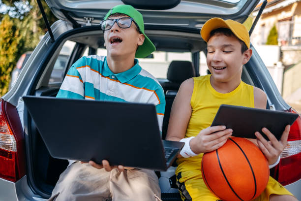 istock Teenagers sitting in car trunk using digital tablet before leaving on sport training 2173801248