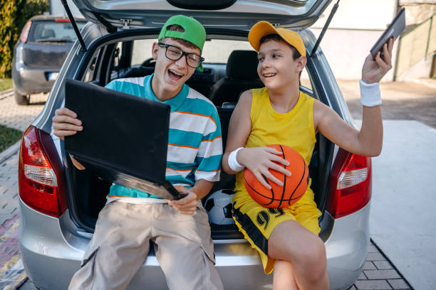 istock Teenagers sitting in car trunk using digital tablet before leaving on sport training 2173801250