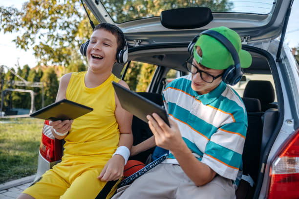 istock Teenagers sitting in car trunk using digital tablet before leaving on sport training 2173801314