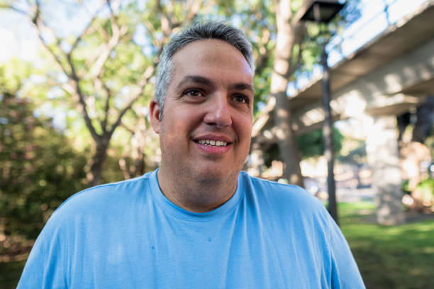 Adult man with gray hair is smiling outdoors while wearing a blue shirt