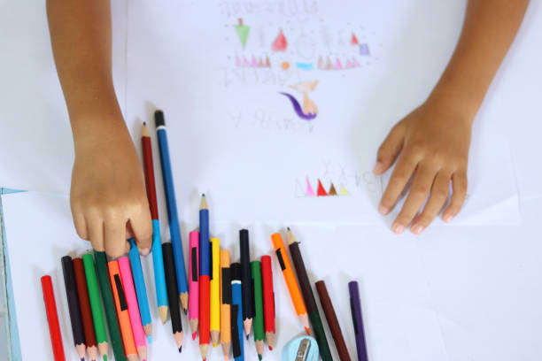 There are students coloring in the classroom on the desks.