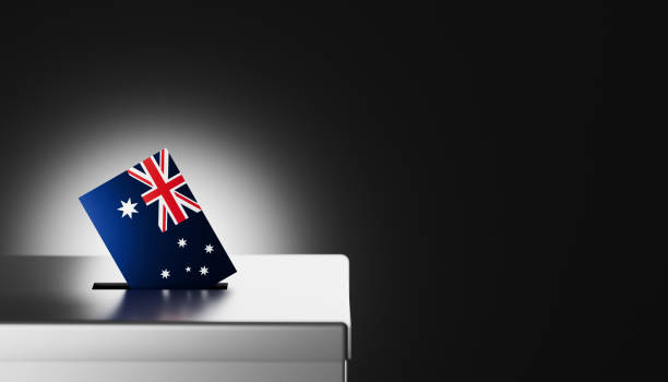 The Australian flag, with its distinctive Union Jack and stars of the Southern Cross, is shown being placed into a ballot box, symbolizing the democratic process and voter participation in Australia. This image highlights themes of national pride, political responsibility, and civic duty, making it ideal for illustrating Australian elections, government processes, and the importance of voting rights. Perfect for use in news articles, educational content, and social media posts related to Australian democracy, elections, and civic engagement.