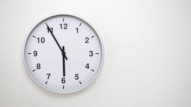 istock Minimalist White Clock with Silver Frame Striking 17.55/05.55 on White Background  Perfect for Time Management and Corporate Campaigns 2173833499
