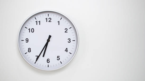 istock Minimalist White Clock with Silver Frame Striking 18.35/06.35 on White Background  Perfect for Time Management and Corporate Campaigns 2173833523