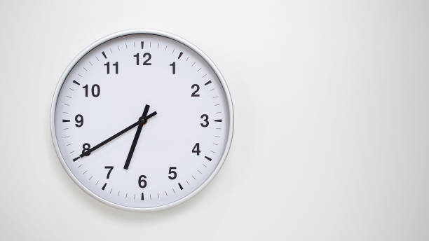 istock Minimalist White Clock with Silver Frame Striking 18.40/06.40 on White Background  Perfect for Time Management and Corporate Campaigns 2173833533