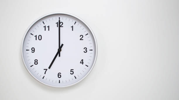 istock Minimalist White Clock with Silver Frame Striking 19.00/07.00 on White Background  Perfect for Time Management and Corporate Campaigns 2173833537