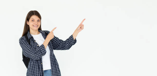 istock Hey look. Smiling pretty female model pointing fingers right at empty space and inviting to check it out, showing advertisement on white background. 2173836726