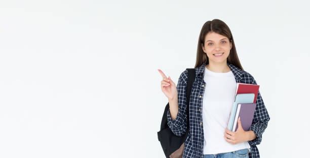istock Hey look. Smiling pretty female model pointing fingers left at empty space and inviting to check it out, showing advertisement on white background. Girl with notepads in hands. 2173836746